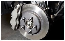 A close up of the brake disc and pads on a car